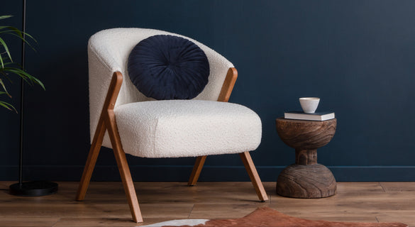 White armchair with a blue cushion against a dark blue wall