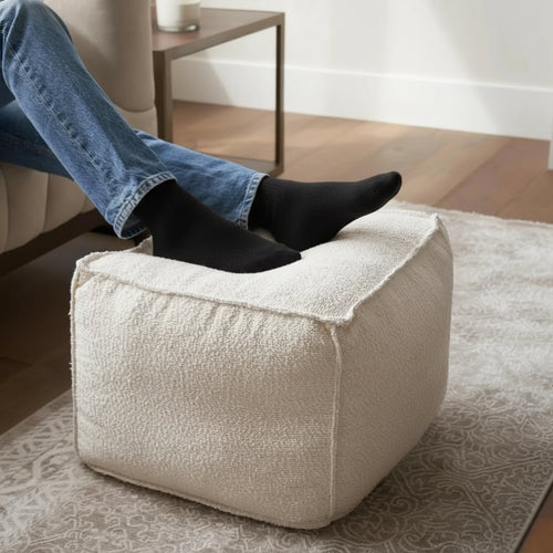 Lightweight boucle pouf ottoman by The Finishing Touch Decor, round footrest with soft fabric and modern design for living room decor.
