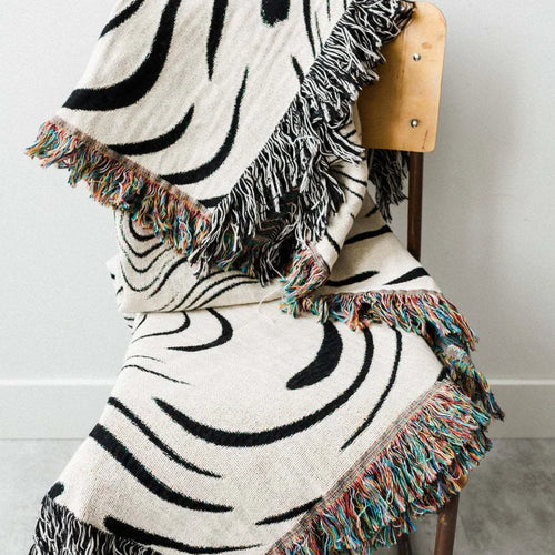 Abstract wavy ink swirl fringed throw blanket by The Finishing Touch Decor, featuring a flowing ink-inspired pattern and fringed edges.