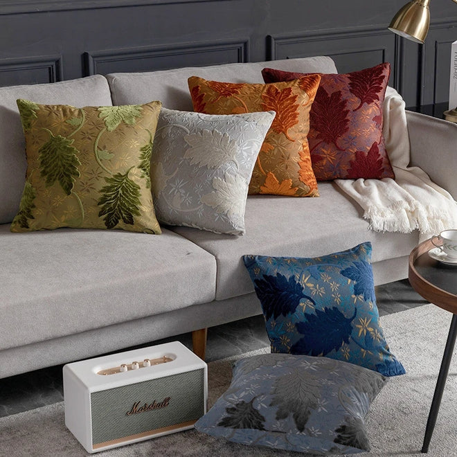 Vibrant embroidered leaf throw pillow cover from The Finishing Touch Decor, featuring colorful leaf patterns on fabric.