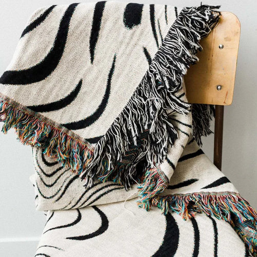 Abstract wavy ink swirl fringed throw blanket by The Finishing Touch Decor, featuring flowing ink-inspired patterns and textured fringe.