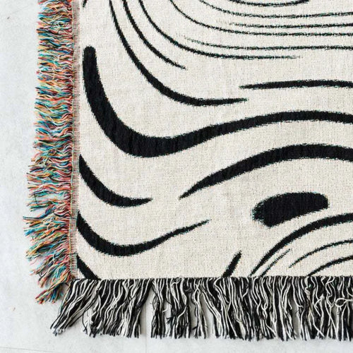 Abstract wavy ink swirl fringed throw blanket by The Finishing Touch Decor, showcasing a stylish, textured design in vibrant colors.
