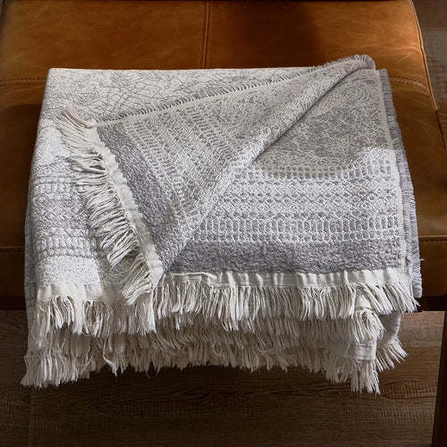 Soft grey gauze blanket made of pure cotton from The Finishing Touch Decor, shown draped over a bed for cozy comfort.