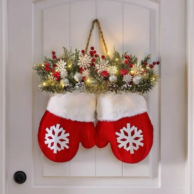 Red mittens with white snowflakes hanging on a door, filled with Christmas decorations.
